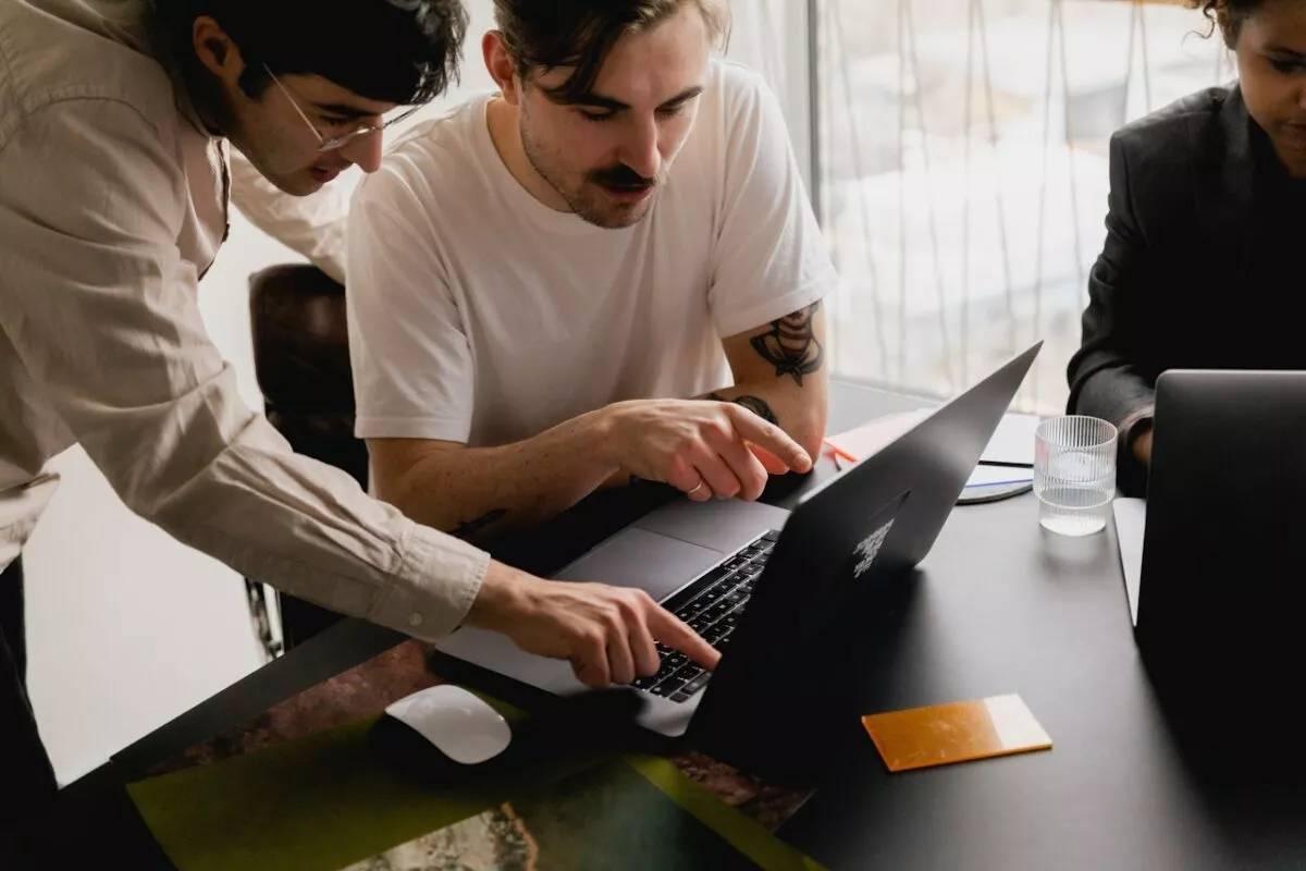 Picture of people collaborating around one laptop